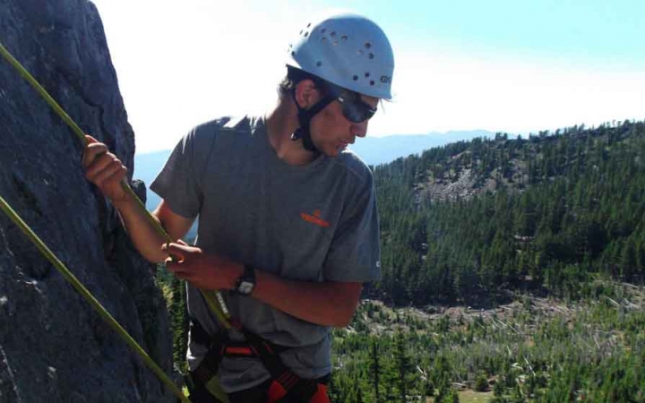 a student looks down while rock climbing in oregon